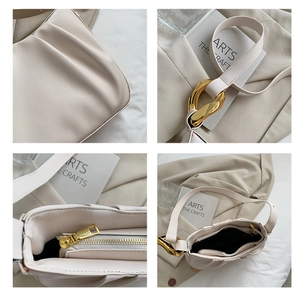 Detailed macro view of the cream pleated bucket bag featuring a bold gold chain link buckle