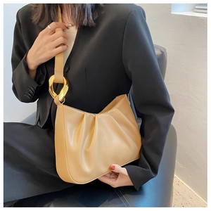 Detail of light khaki pleated cloud bag with elegant large golden metal hardware rings