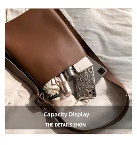 Spacious interior of brown PU leather bucket bag showing umbrella, notebook, and phone