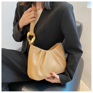 Detail of khaki pleated dumpling bag with elegant oversized golden chain link hardware