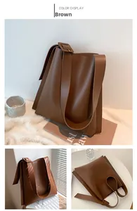 Detailed view of the brown matte leather tote bag featuring a wide adjustable buckle strap