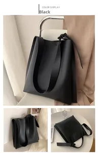 Close-up of black PU leather tote bag with wide strap and adjustable metal buckle detail