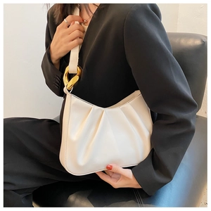 Close-up of white ruched cloud bag featuring a bold chunky gold chain link accent