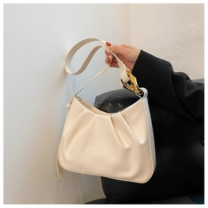 Close-up of beige ruched cloud bucket bag with chunky gold chain hardware and shoulder strap