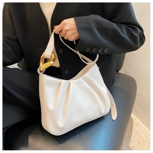 Close-up of white pleated cloud bag with chunky gold chain strap on black blazer