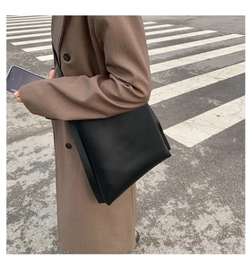 Detail of the minimalist black PU leather crossbody bag featuring a spacious accordion side design