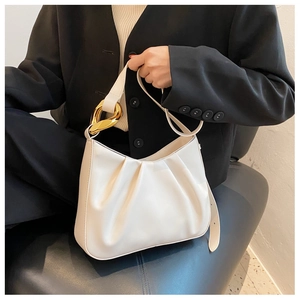 Detail of cream pleated cloud bucket bag featuring a thick gold chain link accent