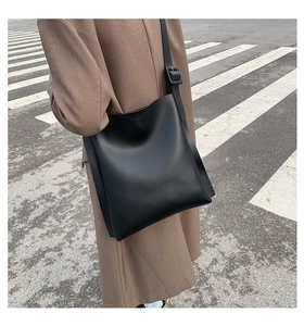 Outdoor shot of a black matte leather tote bag with wide strap on a model for daily commute