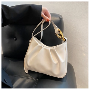 Close-up of off-white ruched cloud bucket bag featuring bold gold chain hardware detail