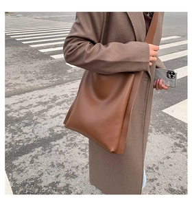 Side view of a large dark brown leather tote bag against a city street background