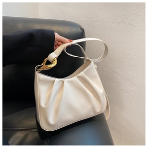 Detail of cream pleated cloud bag featuring retro gold geometric hardware and soft texture