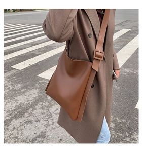 Detailed view of the wide shoulder strap and large buckle on a dark brown leather tote