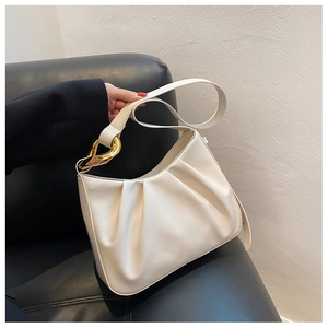Detail of creamy white pleated shoulder bag with gold chain accent on black leather