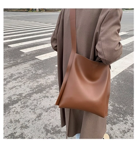 Brown matte leather tote bag with wide shoulder strap shown on a model from behind
