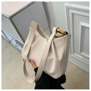 Close-up of cream pleated bucket bag with decorative chunky gold chain link details
