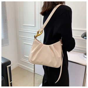 Detail of cream pleated cloud bag with chunky gold chain links on the shoulder strap