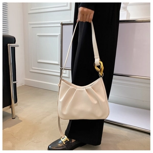 Detail showing cream pleated cloud bag with elegant gold chain hardware on shoulder strap