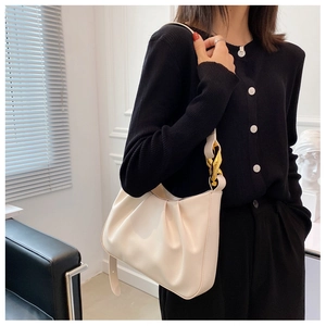 Detail of cream pleated cloud bag featuring premium leather and chunky gold chain strap