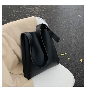 Detail of adjustable wide shoulder strap on a black minimalist leather tote bag