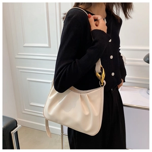Detailed side view of beige pleated cloud bag with stylish gold metal buckles on strap