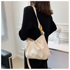 Detail of cream pleated cloud bag with gold chain strap on shoulder shown from behind