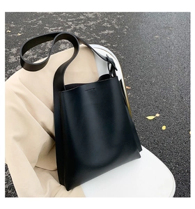Detail view of a black minimalist tote bag with smooth matte leather and wide shoulder strap