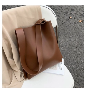 Close-up of a large capacity dark brown tote bag with matte leather texture and wide strap
