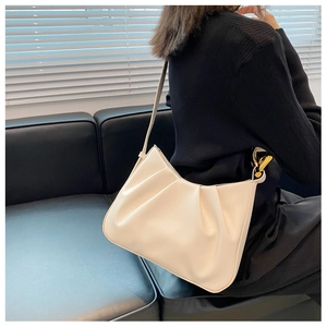 Detail of off-white pleated hobo bag with gold ring buckle worn on shoulder