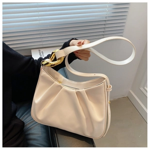 Close-up of cream pleated bucket bag with large gold metal rings on the handle
