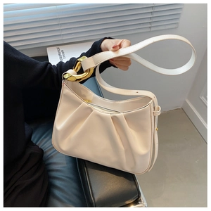 Detail of cream pleated cloud bucket bag with bold gold ring hardware and metal zipper