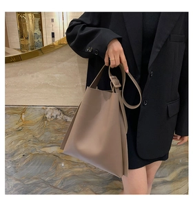 Detail of taupe leather tote bag featuring unique folded side wings and adjustable strap