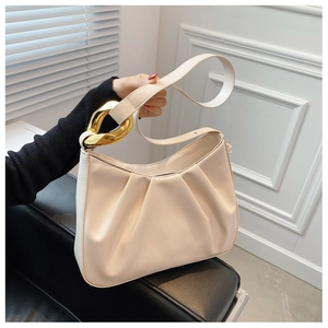 Close-up of pleated beige bucket bag with decorative gold metal rings and textured surface