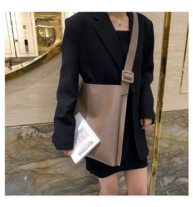Model showing large khaki leather tote bag on shoulder in elegant marble setting