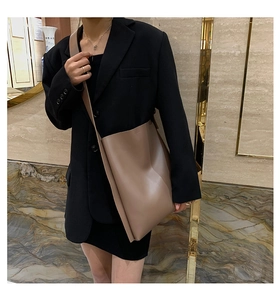 Brown leather tote bag worn by model in black suit for daily commuting style