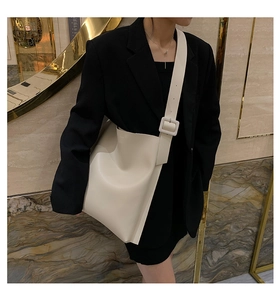 Detail of cream leather tote bag with wide strap and large square buckle on shoulder