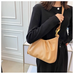 Detail of pleated beige bucket bag with gold metallic hardware on a shoulder strap