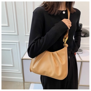 Detail of light camel ruched bucket bag with gold metal accents and textured faux leather