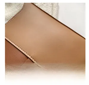 Détail du sac bandoulière en cuir beige montrant des panneaux bicolores et coutures blanches