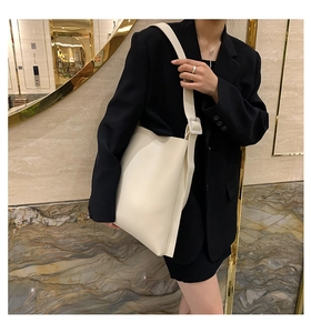 Minimalist cream tote bag with wide strap styled with a black suit for professional office look