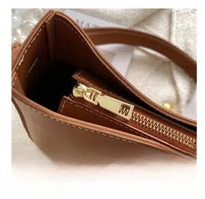 Détail du sac de selle en cuir marron avec fermeture éclair dorée et coutures