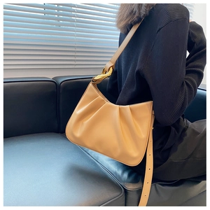 Detail of adjustable leather strap and golden metal hardware on pleated cloud bag