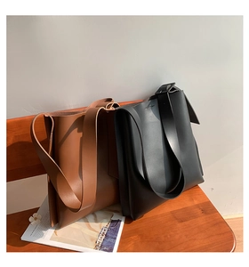 Detailed view of brown and black large leather tote bags on a wooden bench