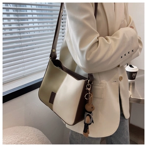 Détail du sac à bandoulière bicolore vert olive avec un pendentif lapin mignon et stylé