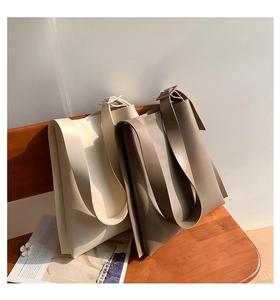 Detail of minimalist cream and taupe leather tote bags on a wooden bench setting