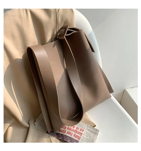 Close-up of brown tote bag strap detail with square buckle on a minimalist background