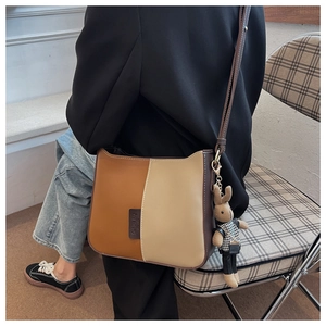 Gros plan du sac seau bicolore avec un adorable pendentif lapin en peluche sur la bandoulière