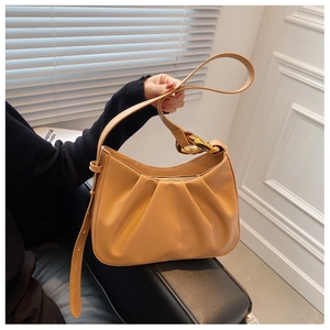 Close-up of mustard yellow bucket bag featuring pleated cloud design and gold chain detail