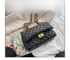Size comparison of a black quilted chain bag with gold hardware against a mobile phone