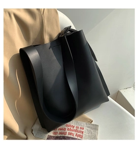 Detail view of the sleek matte leather texture and integrated strap of this black tote bag