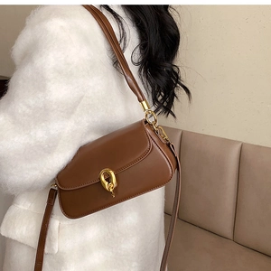 Detailansicht einer braunen Ledertasche mit goldenem Metallverschluss vor hellem Hintergrund